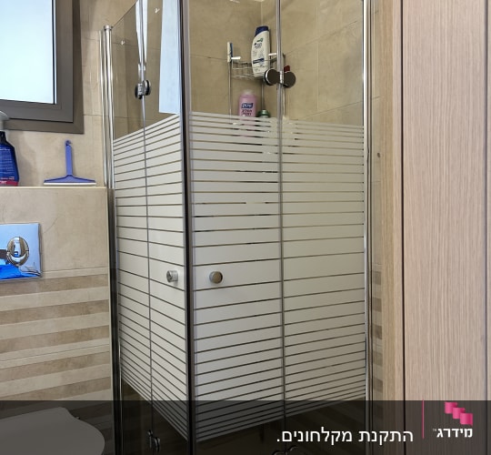 מקלחון זכוכית עם מוצרי רחצה בחדר אמבטיה
